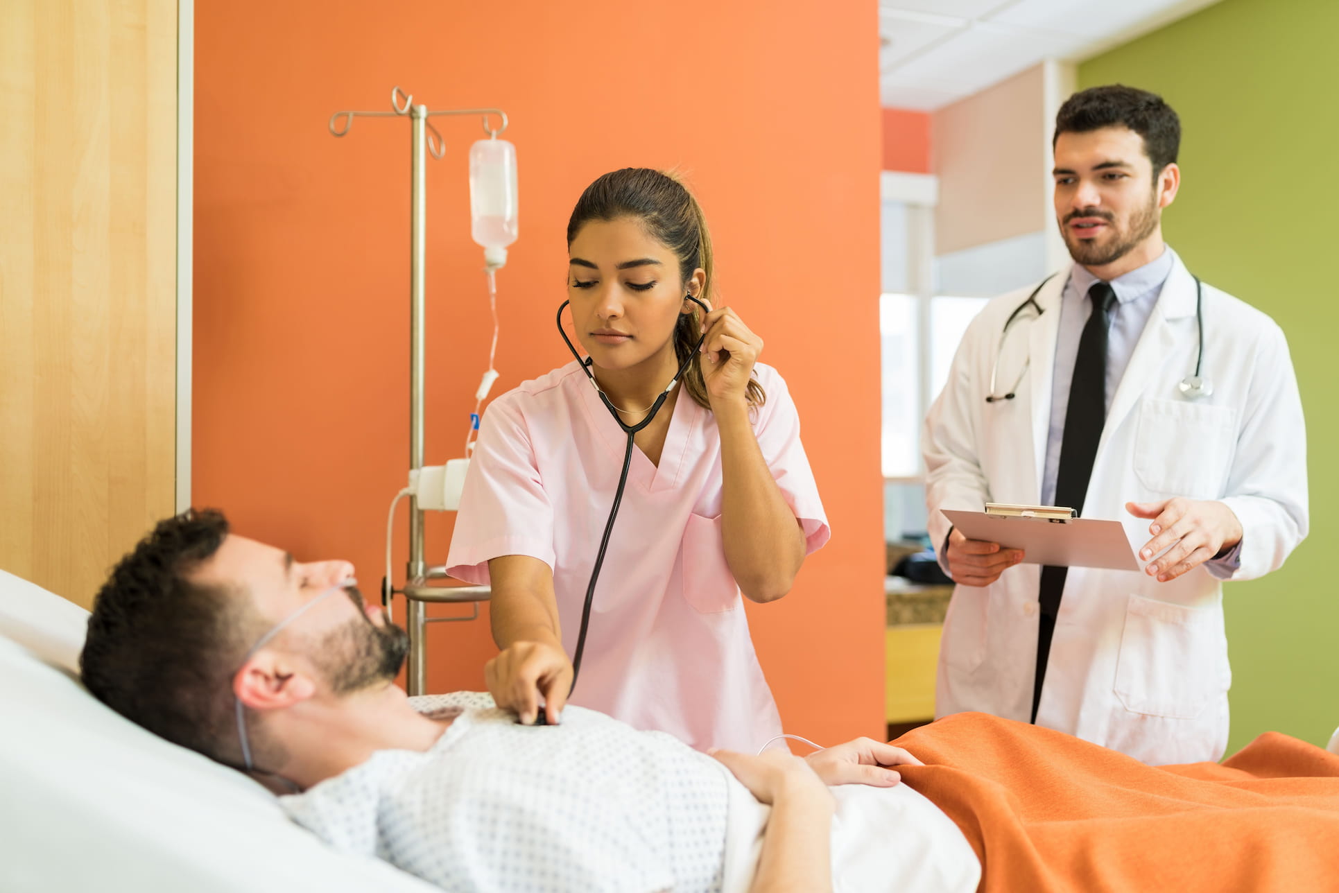 female doctor examining sick patient with stethoscope while male doctor analyzing reports hospital 2 2